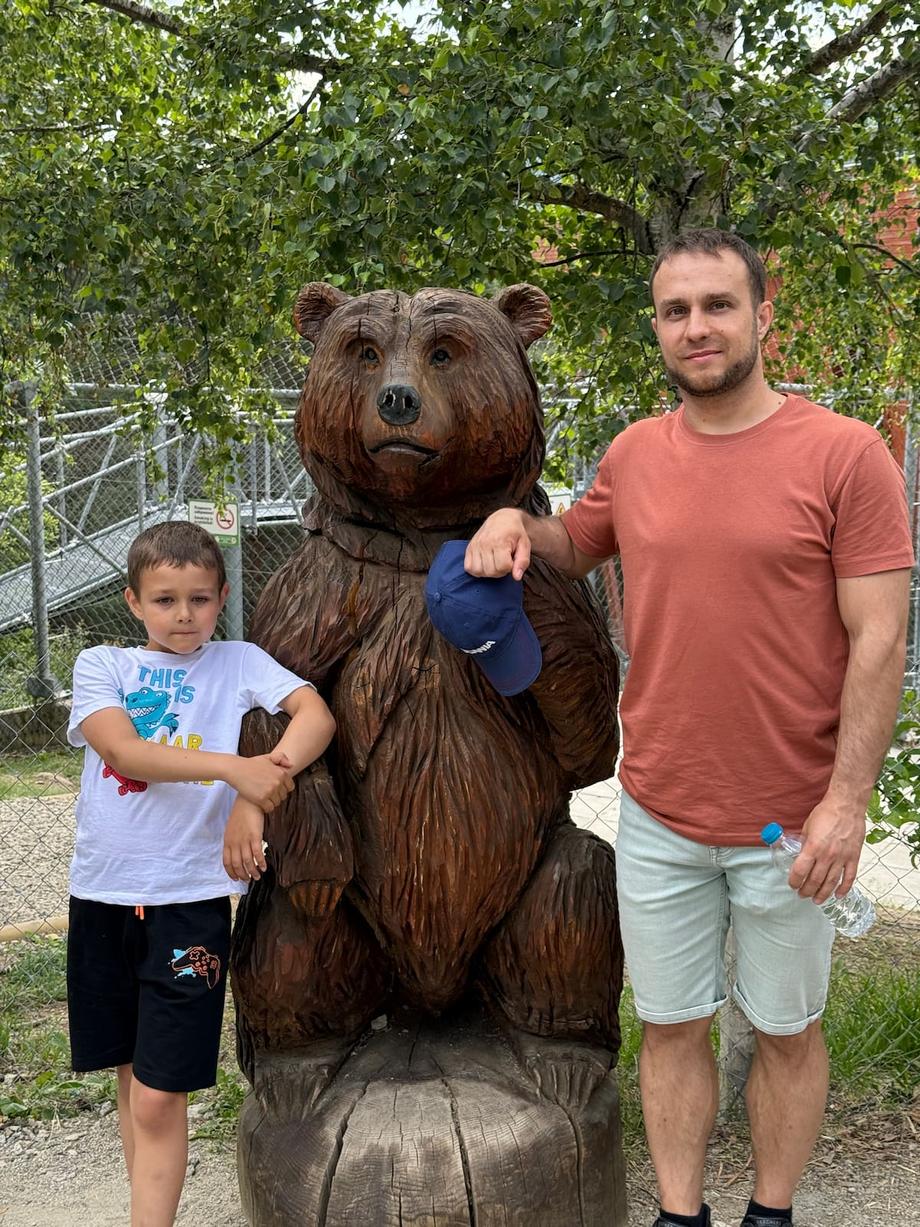 Anton and dad with the bear statue in the mountains